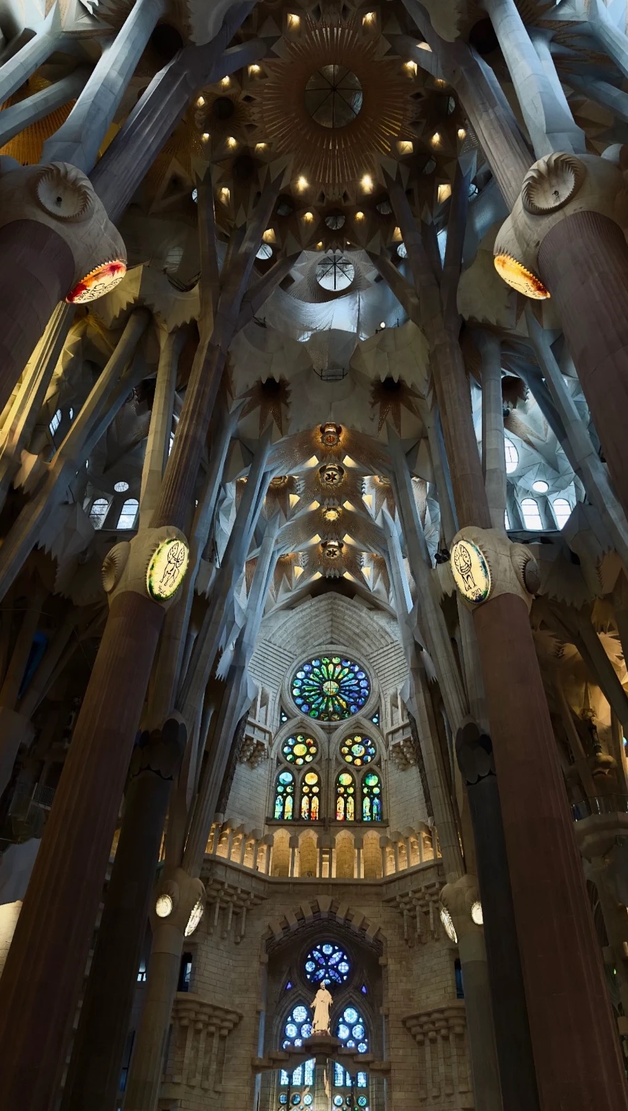 Intérieur de la Sagrada Família : colonnes en forme d'arbres, voûtes éclairées et vitraux colorés